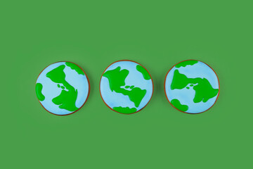 Earth Day concept. Three cookies in shape of Earth on green backdrop.