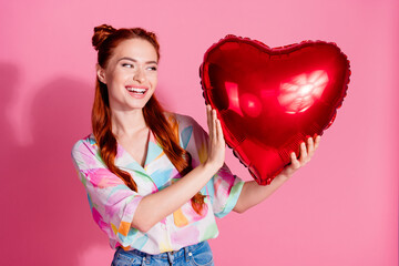 Photo of lovely girl with red tails dressed colorful blouse look at balloon celebrate valentine day isolated on pink color background