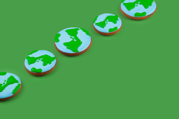 Earth Day concept. Сookies in shape of Earth on green backdrop.