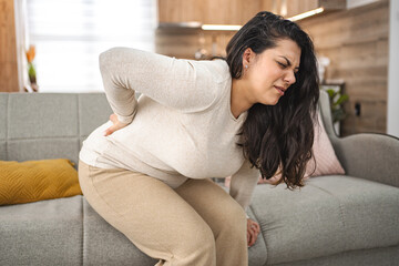Woman suffering with back pain while at home
