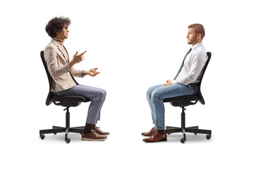 Profile shot of two men sitting in office chairs and talking