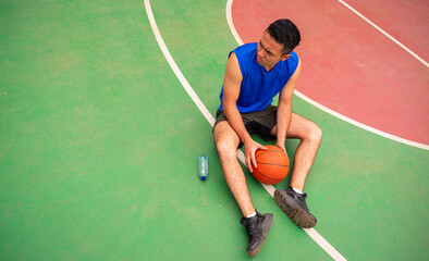 Top view of man taking rest from basketball training  in court in sunny day at summer 