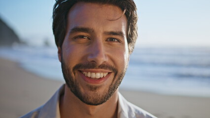 Closeup hispanic man smiling standing on sunny beach. Portrait happy bearded guy