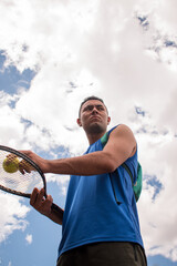Low angle of man holding tennis racket with tennis balls