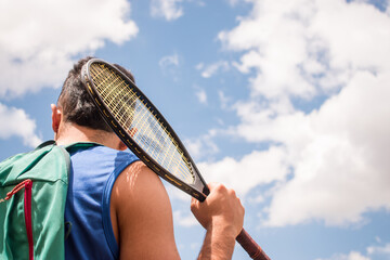 Man back holding tennis racket in sunny day
