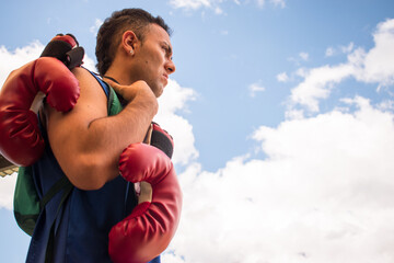 Latin young boxer man training with red boxing gloves in latin outdoors gym