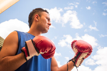 Latin young boxer man training with red boxing gloves in latin outdoors gym