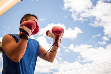 Latin young boxer man training with red boxing gloves in latin outdoors gym