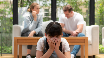 Stressed and unhappy young girl crying and trapped in middle of tension by her parent argument in...