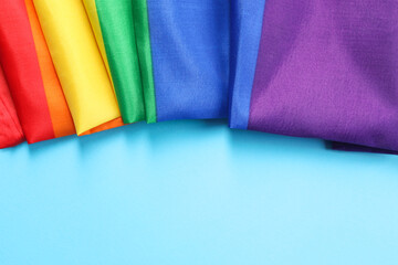 Rainbow LGBT flag on light blue background, top view. Space for text