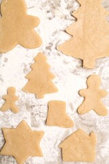 Raw Christmas cookies in different shapes on parchment paper, flat lay