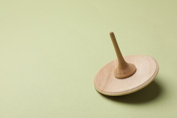 One wooden spinning top on green background, space for text