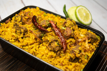Achari beef khichuri biryani rice pulao with cucumber and lemon slice served in dish isolated on wooden table side view of bangladeshi and indian spices lunch food