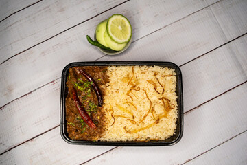 Achari beef pulao biryani rice with cucumber and lemon slice served in dish isolated on wooden...