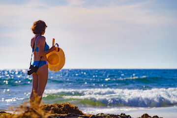 Woman in bikini with camera walk on beach