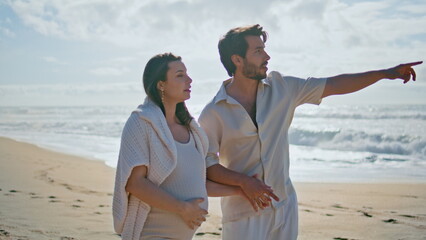 Pregnant couple enjoy sea landscape walking beach sand. Woman expecting baby