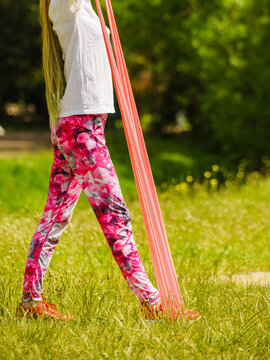 Girl doing exercises outdoor, using resistance fit band.