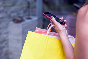 Woman with shopping bags and credit card on the phone in a shopping center, shopping concept.