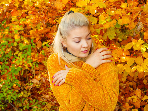 Woman in autumn park warming herself