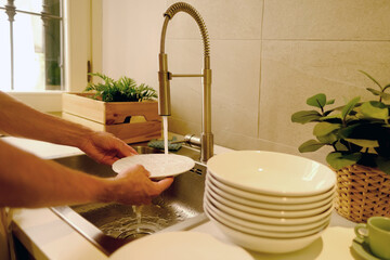 close-up male hands washing dishes, young man doing household chores in modern kitchen, concept...