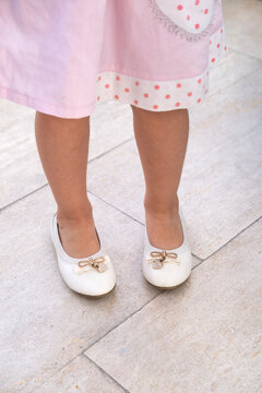Little girl's legs in skirt, wearing white shoes with bows, charming innocence and playfulness of childhood, sense purity, youth and joyous moments being carefree