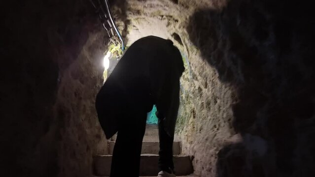 Female traveler walks in narrow tunnels of the Derinkuyu underground city built in BC 1200 in Cappadocia, Turkey.