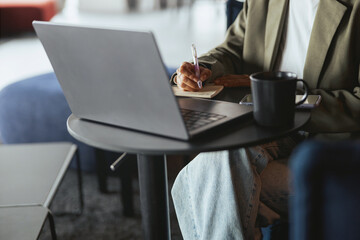 Individual sitting at table with laptop and coffee cup