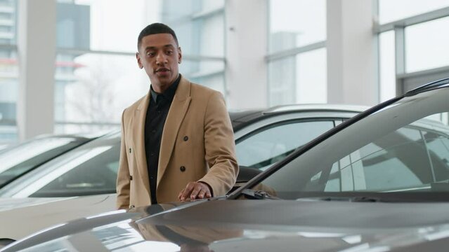 African American man unsure pensive male client customer buyer choose automobile in dealership store ethnic guy millennial think doubt touch car hood dream buying auto expensive purchase in showroom