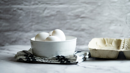 Eggs placed within a bowl atop a white marble surface.