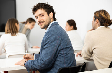 Positive young man turning around and looking at camera during advanced training course in auditory