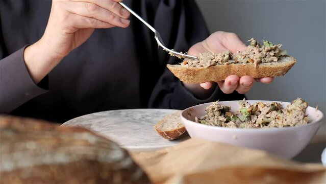 Woman eating fresh toast with homemade tuna spread