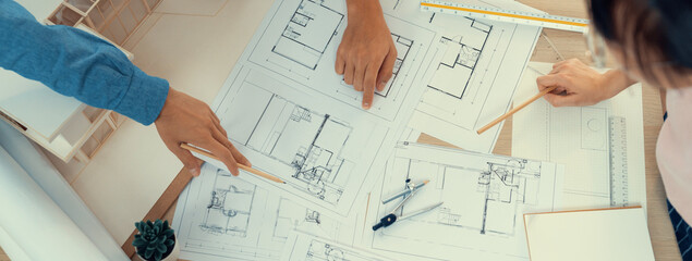 Blueprint architectural document scatter around on meeting table while professional architect engineer hand pointing at blueprint. Creative design teamwork discussion concept. Top view. Burgeoning.