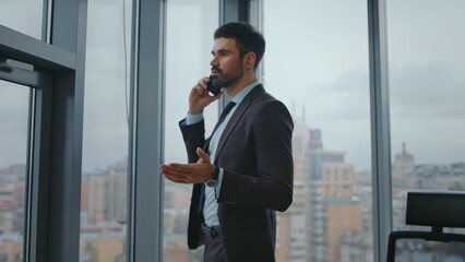 Business manager speaking cellphone looking at window office. Man calling phone.