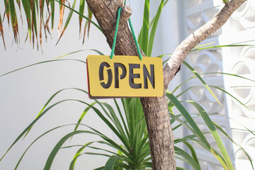 Open sign hanging on tree. Label with text in flat style. Restaurant window. Information welcoming...