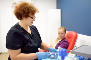A nurse prepare to take blood from a young woman. Taking a blood sample for examination in a modern...