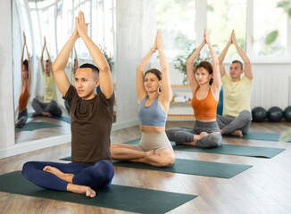 Young man and athletes practice hatha yoga in studio during class. Male lover of active lifestyle on yoga mat perform doing lotus position, padmasana with practice of breathing and greeting namaste