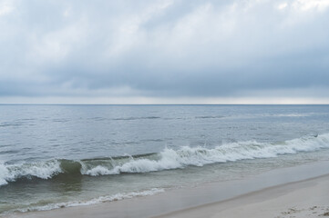 Gentle ocean waves from Atlantic Ocean blue waters breaking and hitting the white sands at Praia Seca beach under summer afternoon clouded sky in Praia Seca district, Araruama, Rio de Janeiro - Brazil