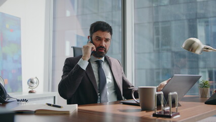Dissatisfied entrepreneur speaking smartphone nervously sitting office close up. - obrazy, fototapety, plakaty