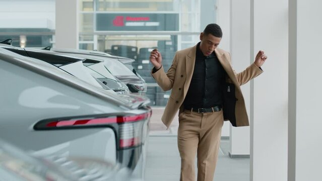 Happy car owner African American guy celebrate dancing excited buying new automobile in showroom auto sale funny man male buyer customer businessman dance in vehicle store shop rent service dealership