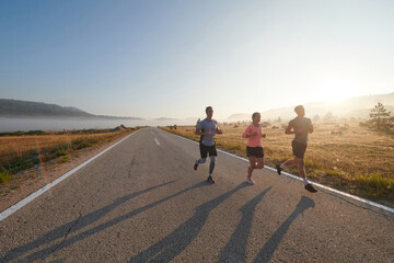 A group of friends, athletes, and joggers embrace the early morning hours as they run through the misty dawn, energized by the rising sun and surrounded by the tranquil beauty of nature