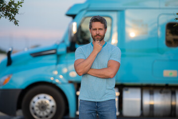 Men driver near lorry truck. Man owner truck driver in t-shirt near truck. Handsome middle aged man trucker trucking owner. Semi trailer, semi trucks. Handsome man posing in front of truck.