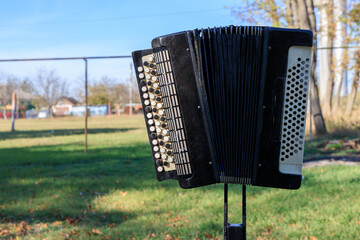 A black and white accordion is sitting on a grassy field