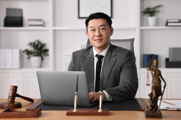 Happy notary working with laptop at wooden table in office