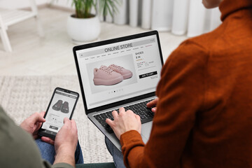 Couple with laptop and smartphone shopping online indoors, closeup