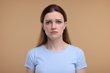 Portrait of sad woman on beige background