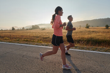 Energized by the beauty of nature, a couple powers through their morning run, their bodies and...