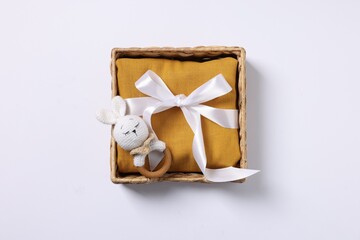 Baby accessory. Rattle and child`s clothes in wicker box on white background, top view
