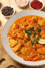 Delicious chicken curry and spices on wooden table