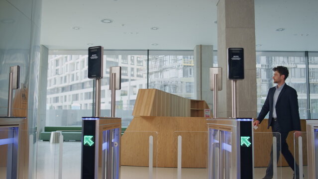 Man entering office automatic gates using electronic card reader at building.