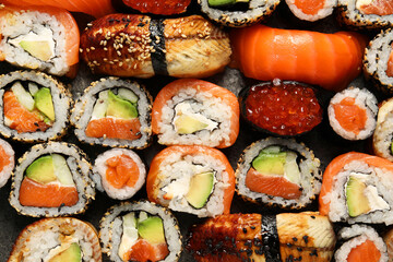 Different tasty sushi rolls as background, top view